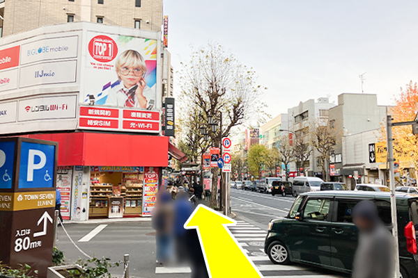 100ｍ程まっすぐ進んで携帯ショップの手前の横断歩道を渡ります。