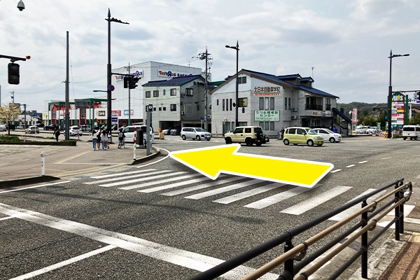 交差点を渡り、奥に大きな看板が見えるので、看板に向かって直進します。
